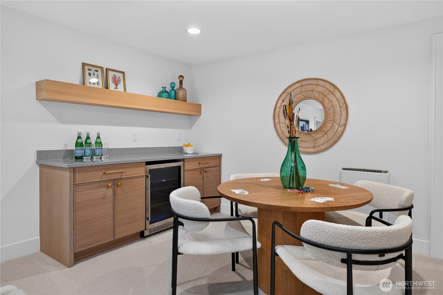 Dining area with a round wooden table, upholstered chairs, and a built-in wet bar.
