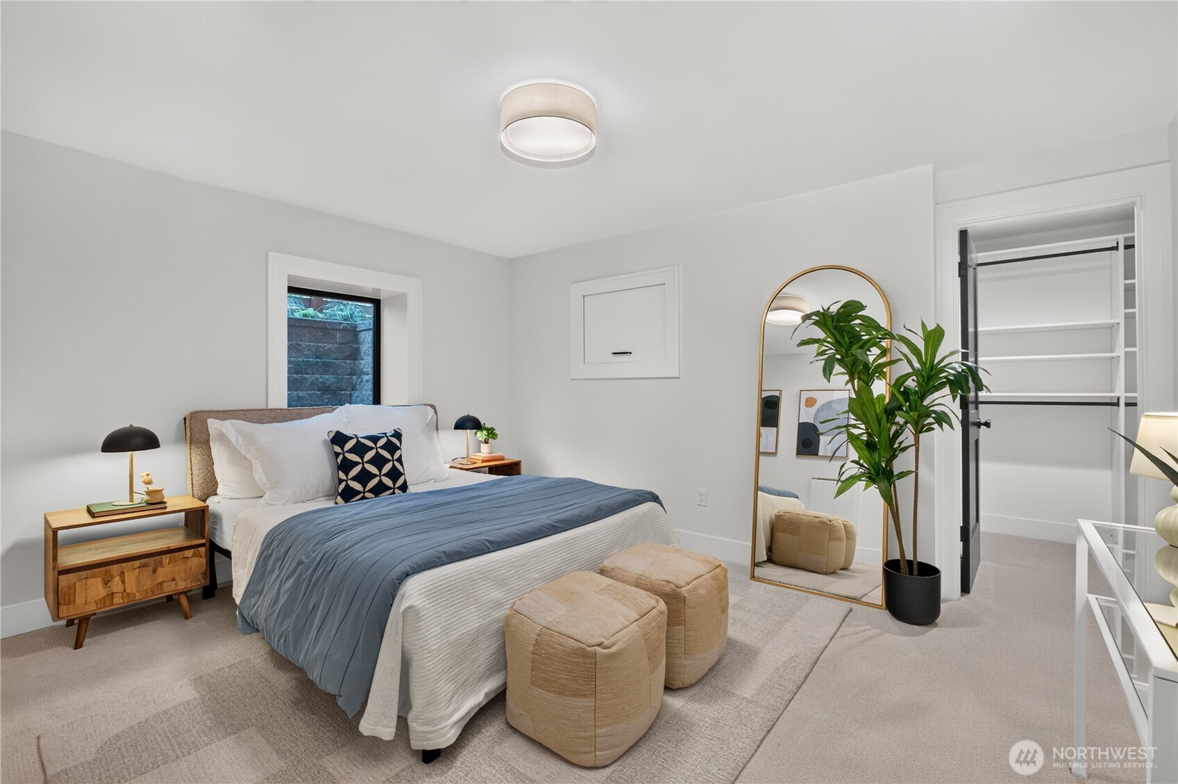 Staged bedroom with blue bedding, an arched mirror, and an open built-in closet.