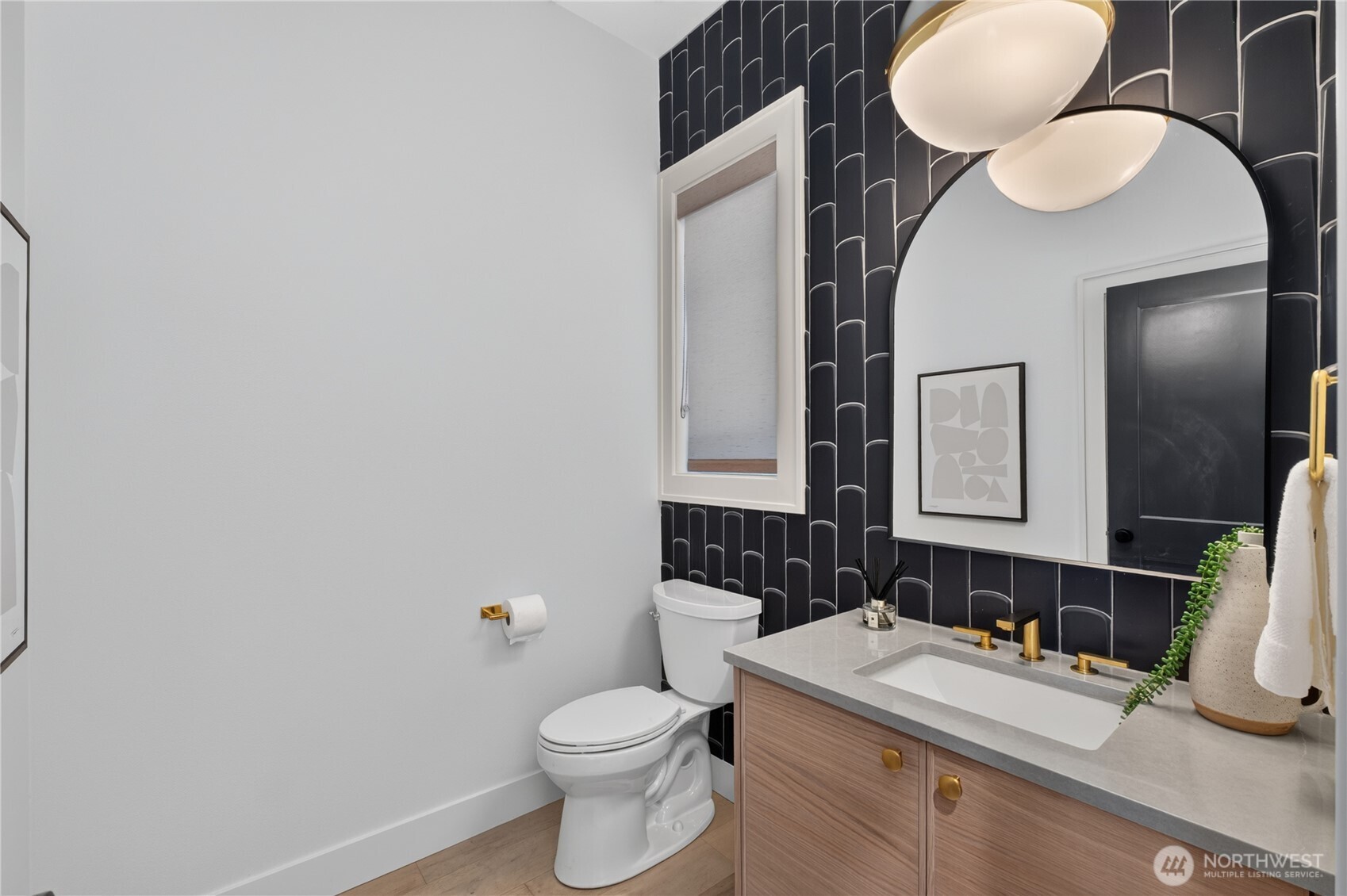 Bathroom with dark patterned tile, a wood vanity, and gold fixtures.