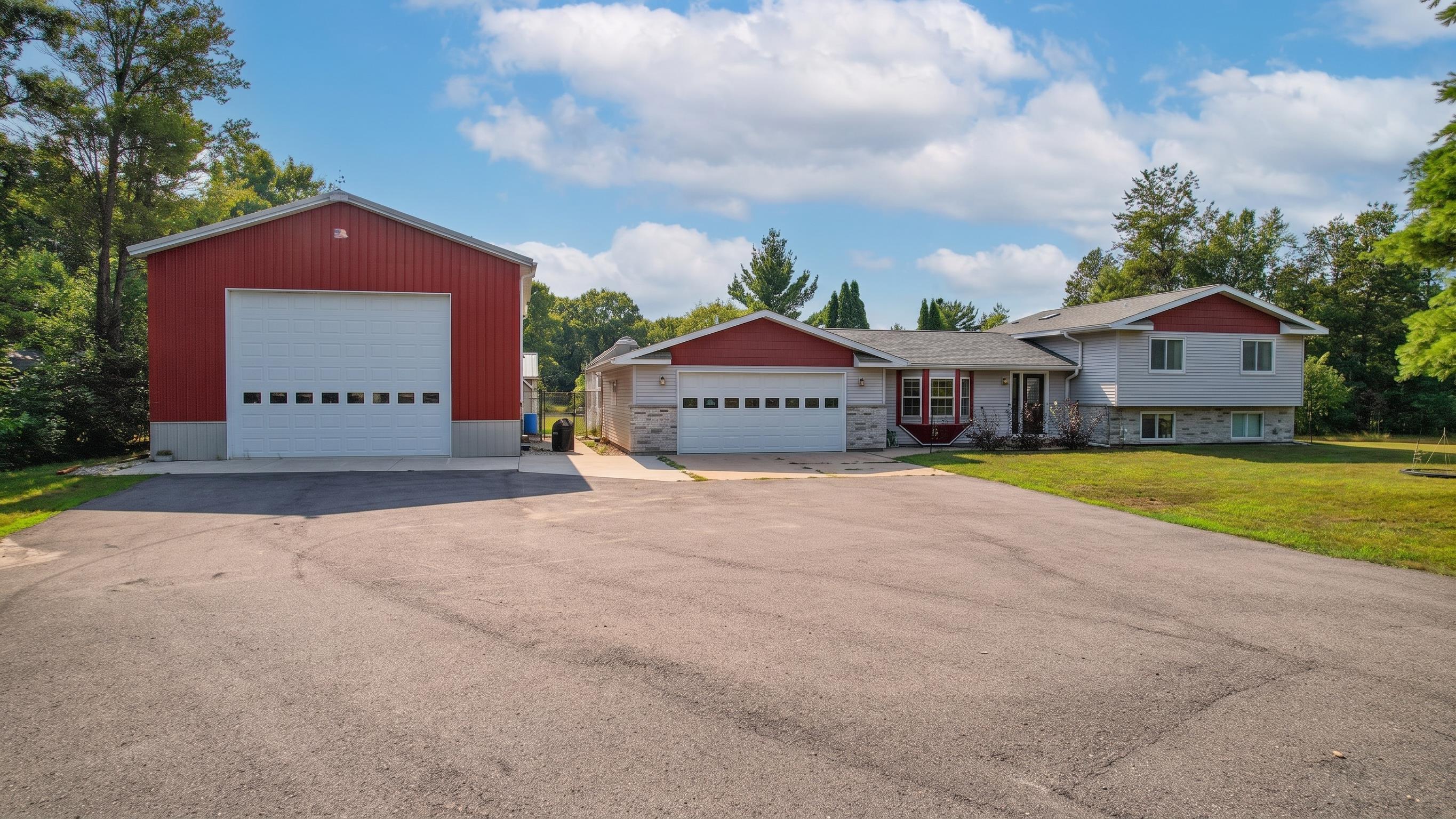 Split-level home beside a large red detached garage, with a broad paved driveway.