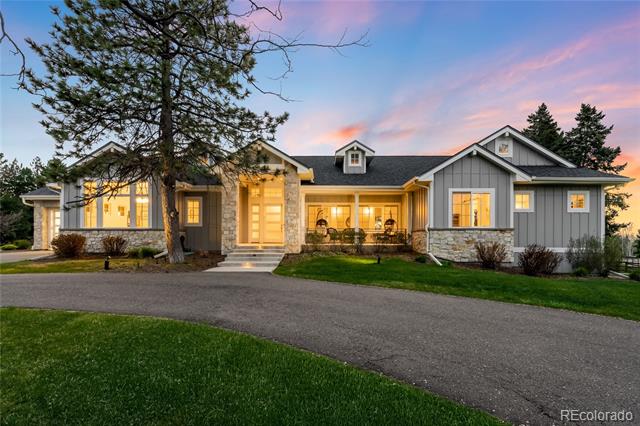 Gray single-story home with stone accents and a curved driveway at dusk.