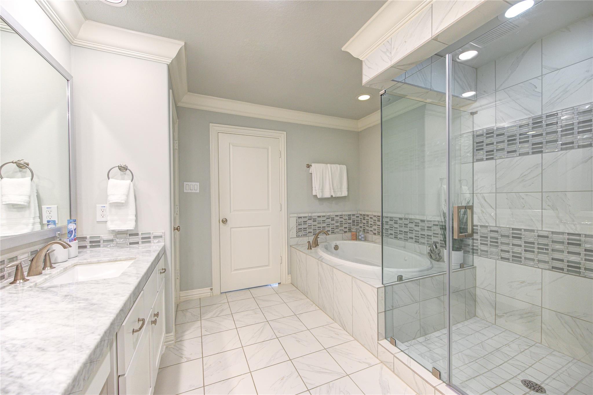Bathroom with a glass walk-in shower, mosaic tile accents, and a built-in soaking tub.