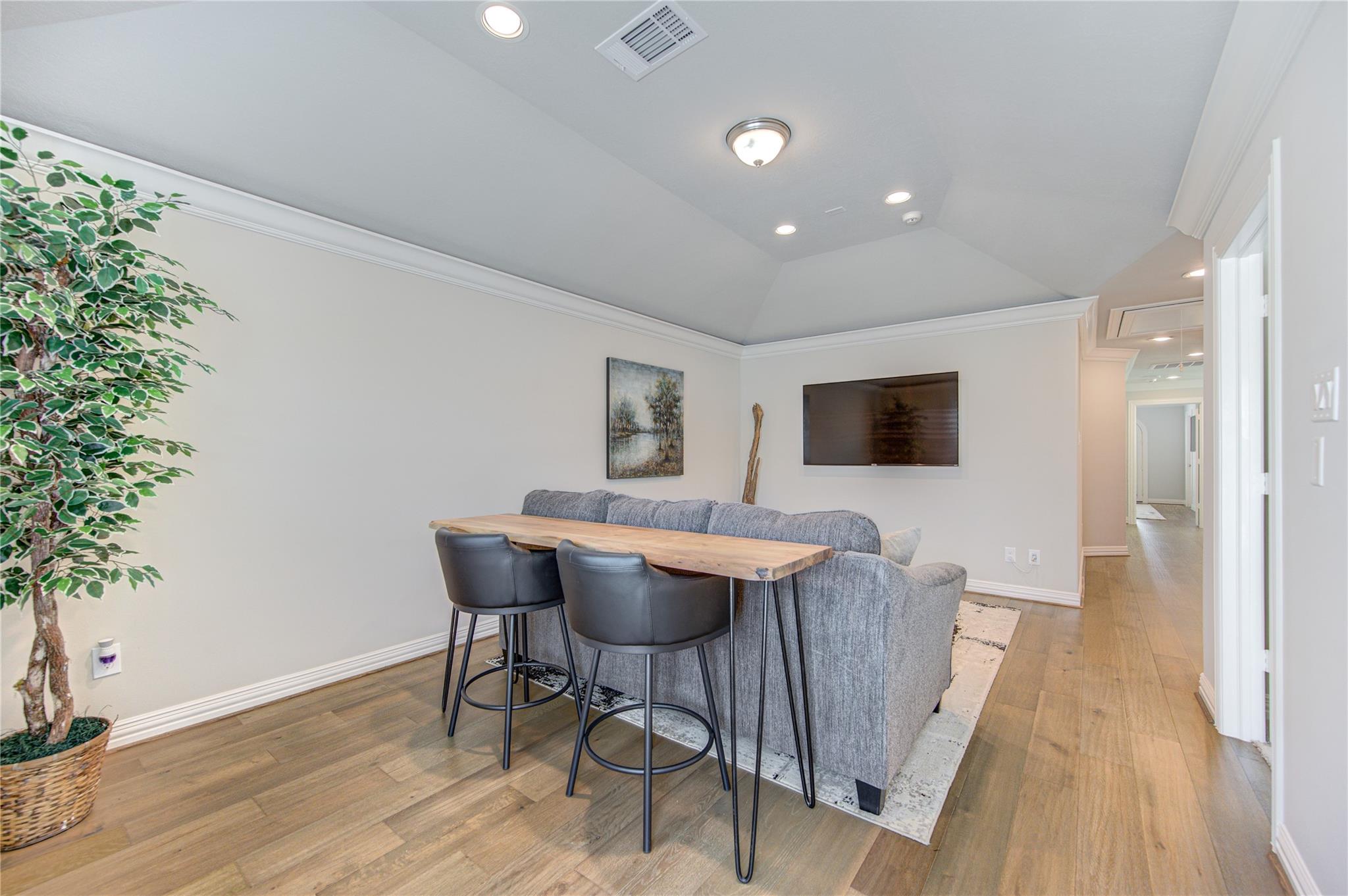Lounge with gray sectional, live-edge table, and wall-mounted television.
