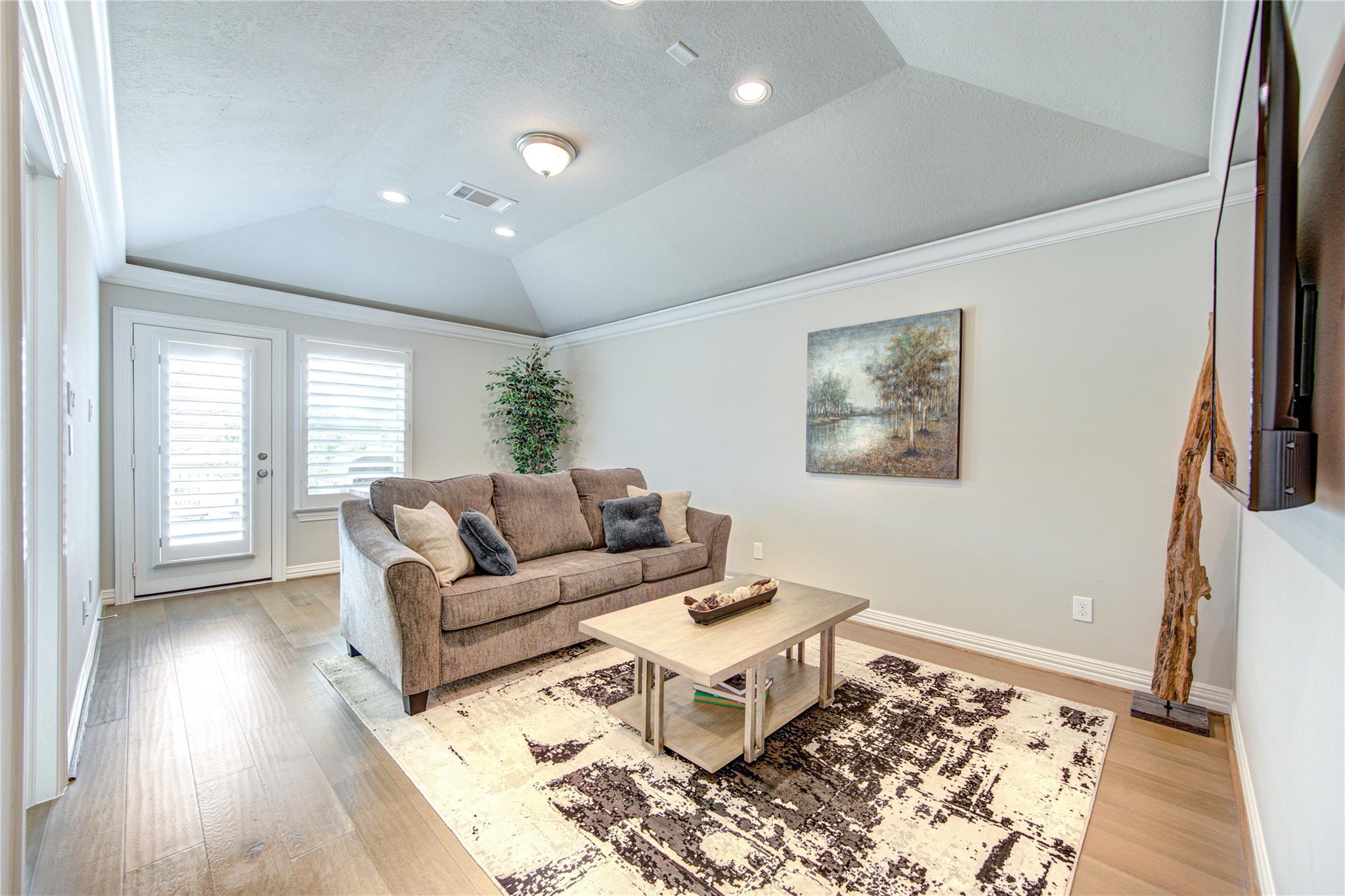 Living room with a brown sofa, patterned rug, and vaulted ceiling.