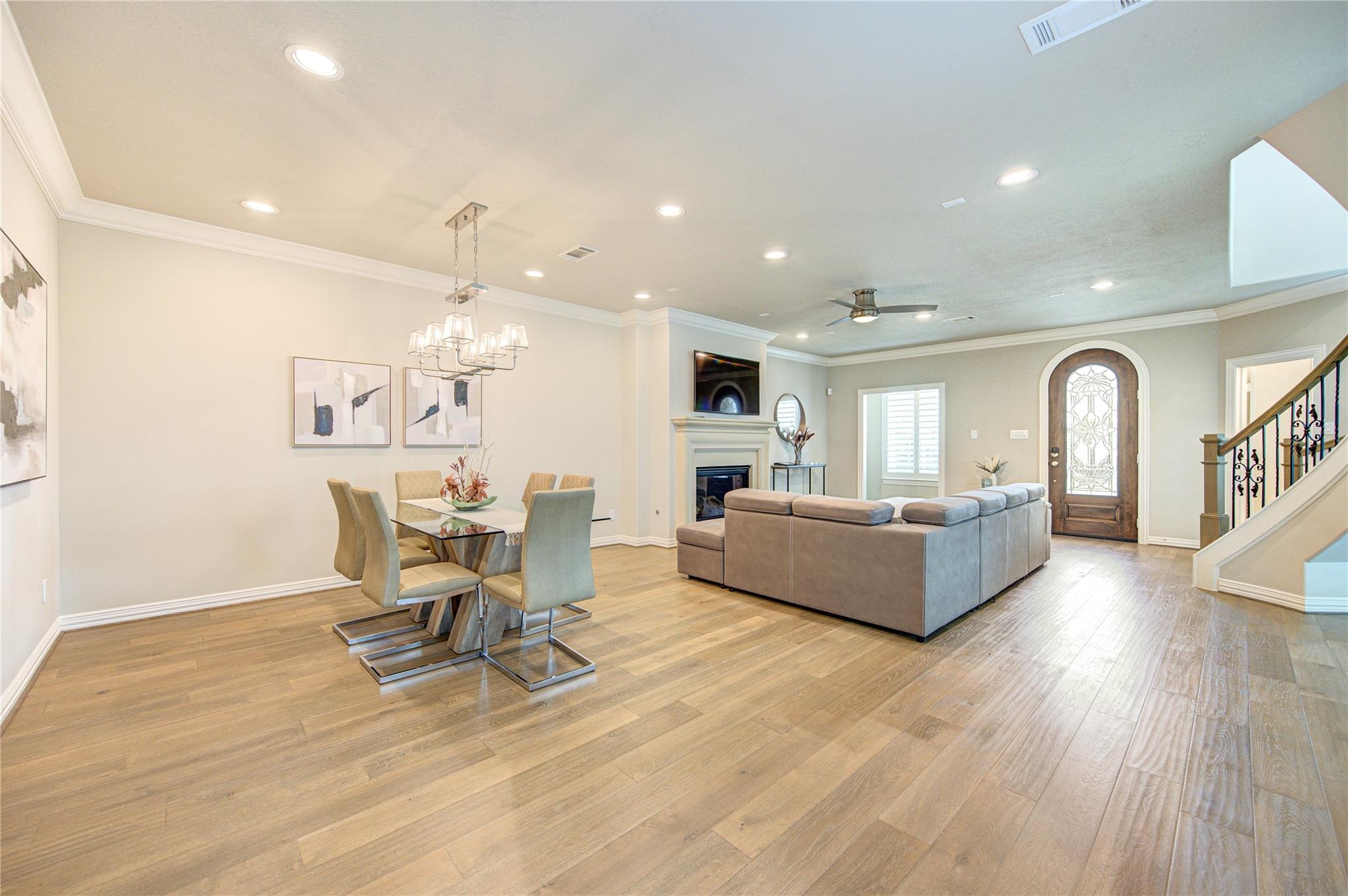 Open-plan living and dining room with a gray sectional, fireplace, and decorative-glass entry door.