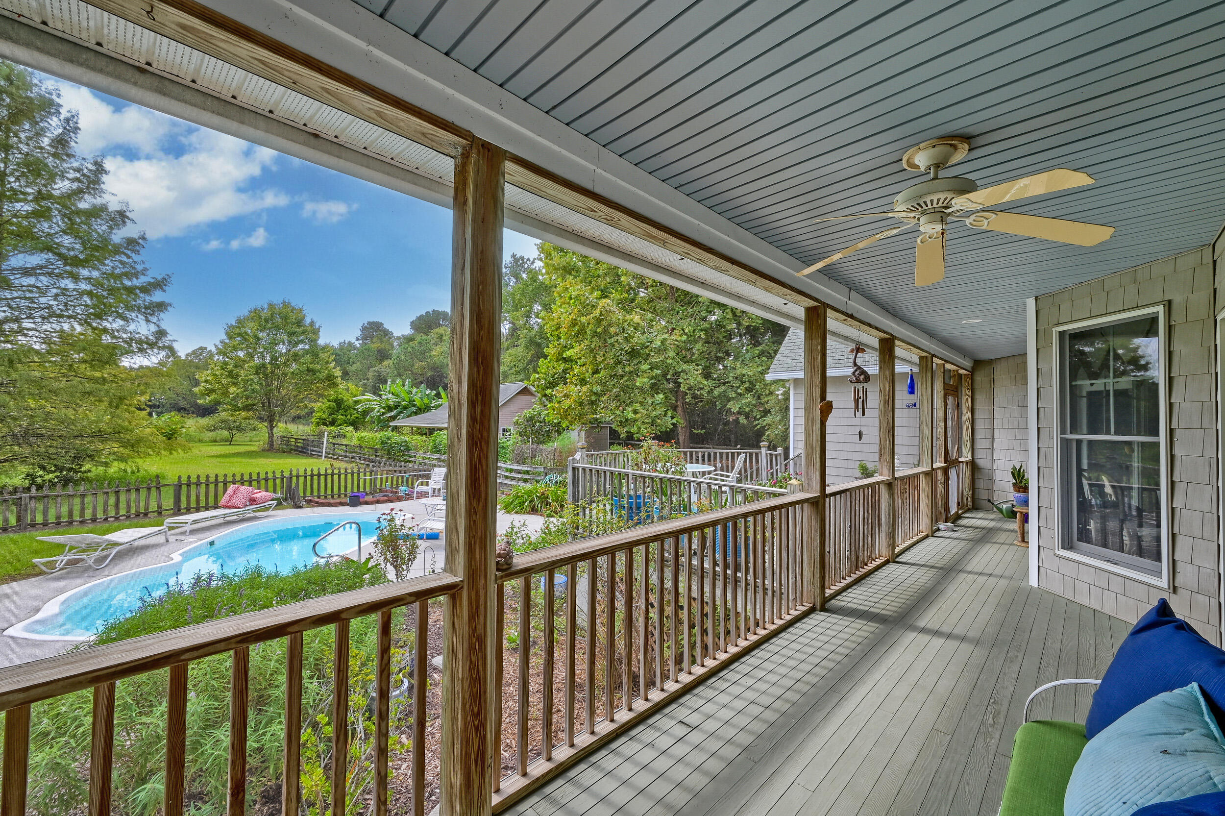 Covered back porch overlooking a swimming pool and tree-lined yard.