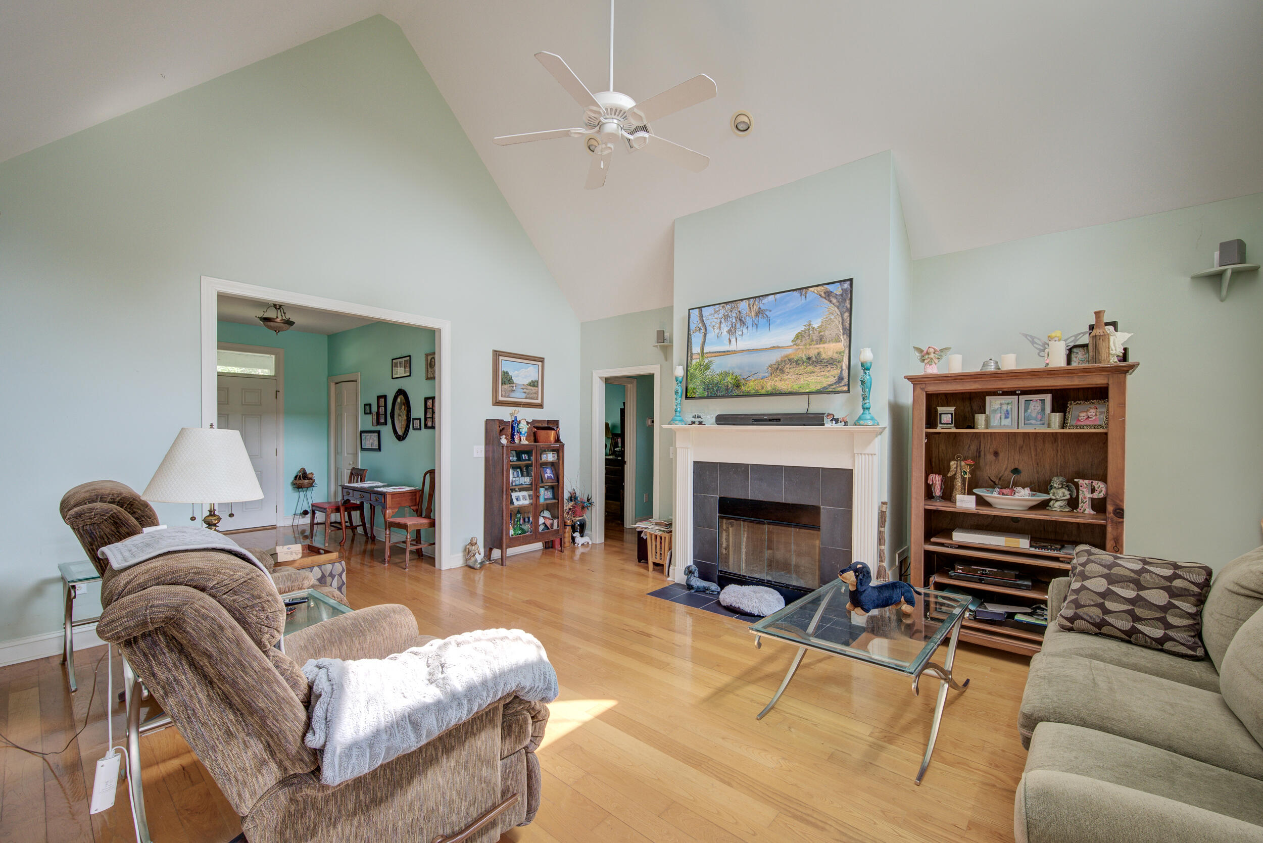Living room with a vaulted ceiling, hardwood floors, and a fireplace between built-in-style display shelves.