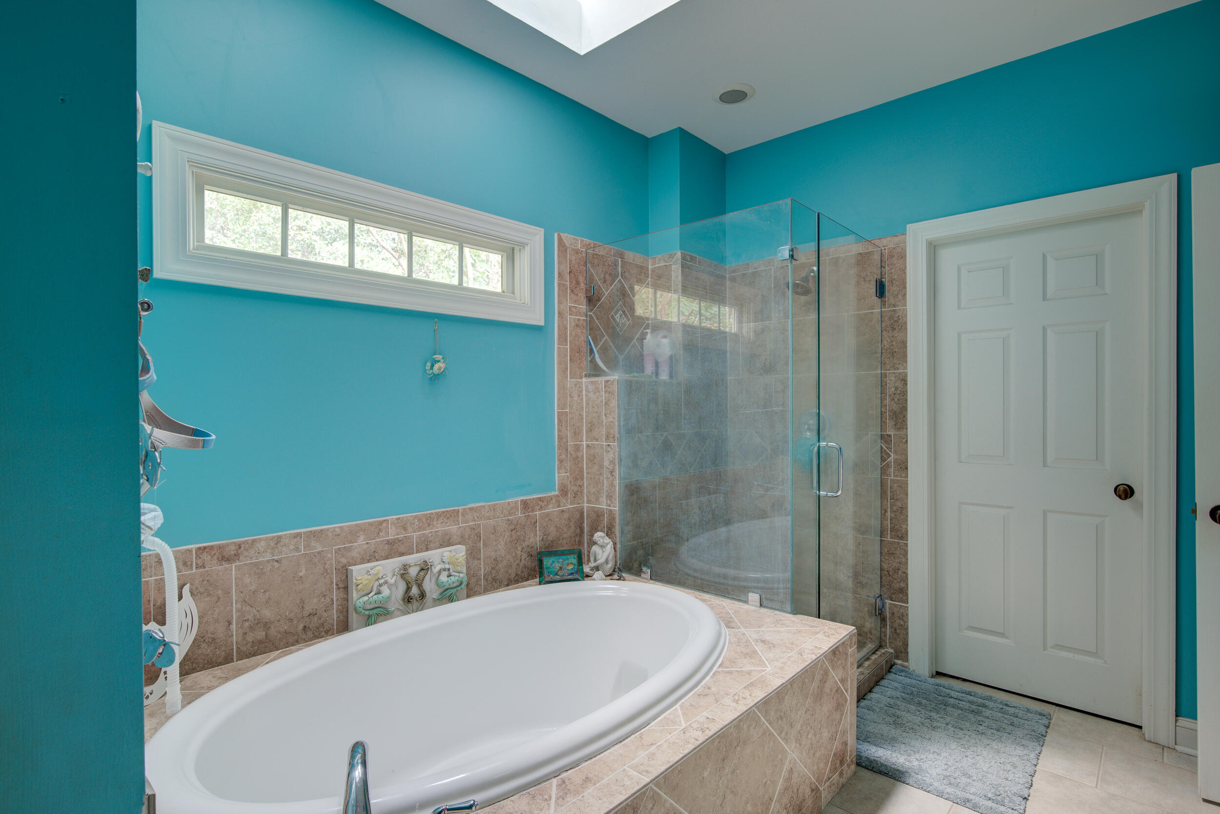 Bathroom with a built-in soaking tub, glass-enclosed shower, and vivid turquoise walls.