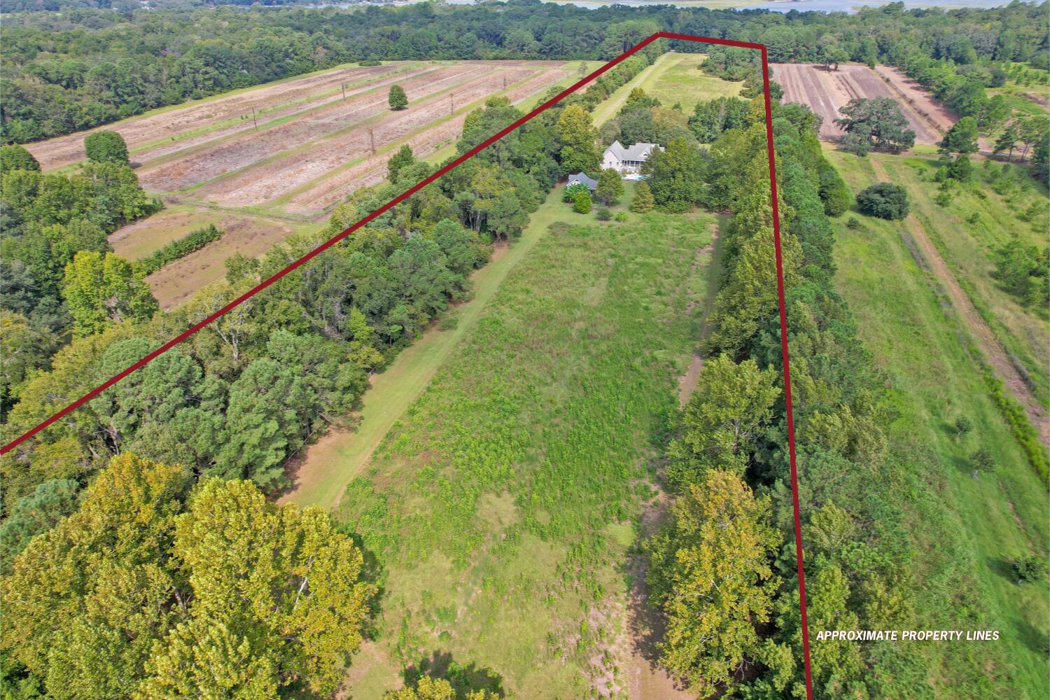 Aerial view of the property outlined in red, with a house amid fields and trees.