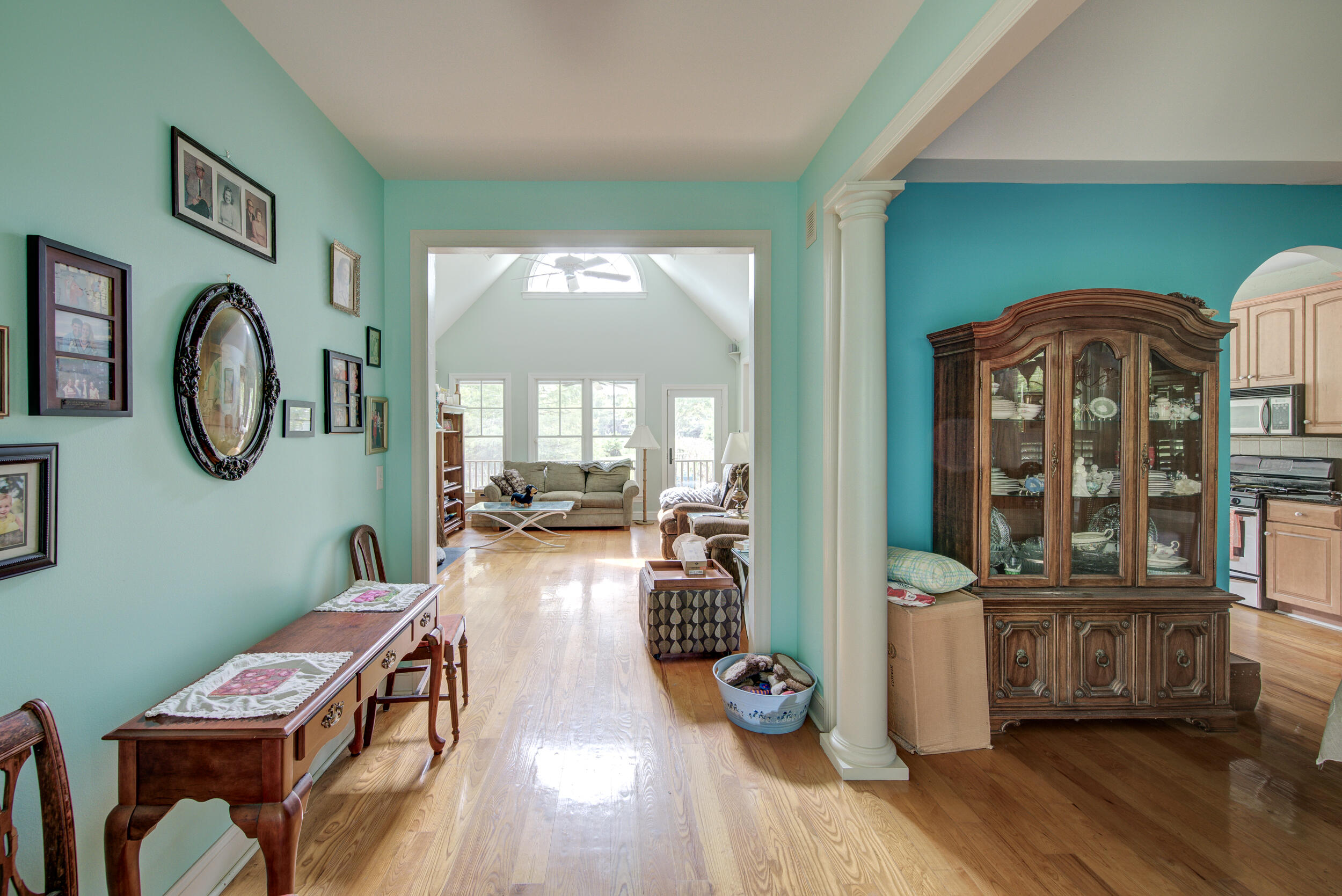 Foyer with aqua walls and wood floors opening into a bright living room.