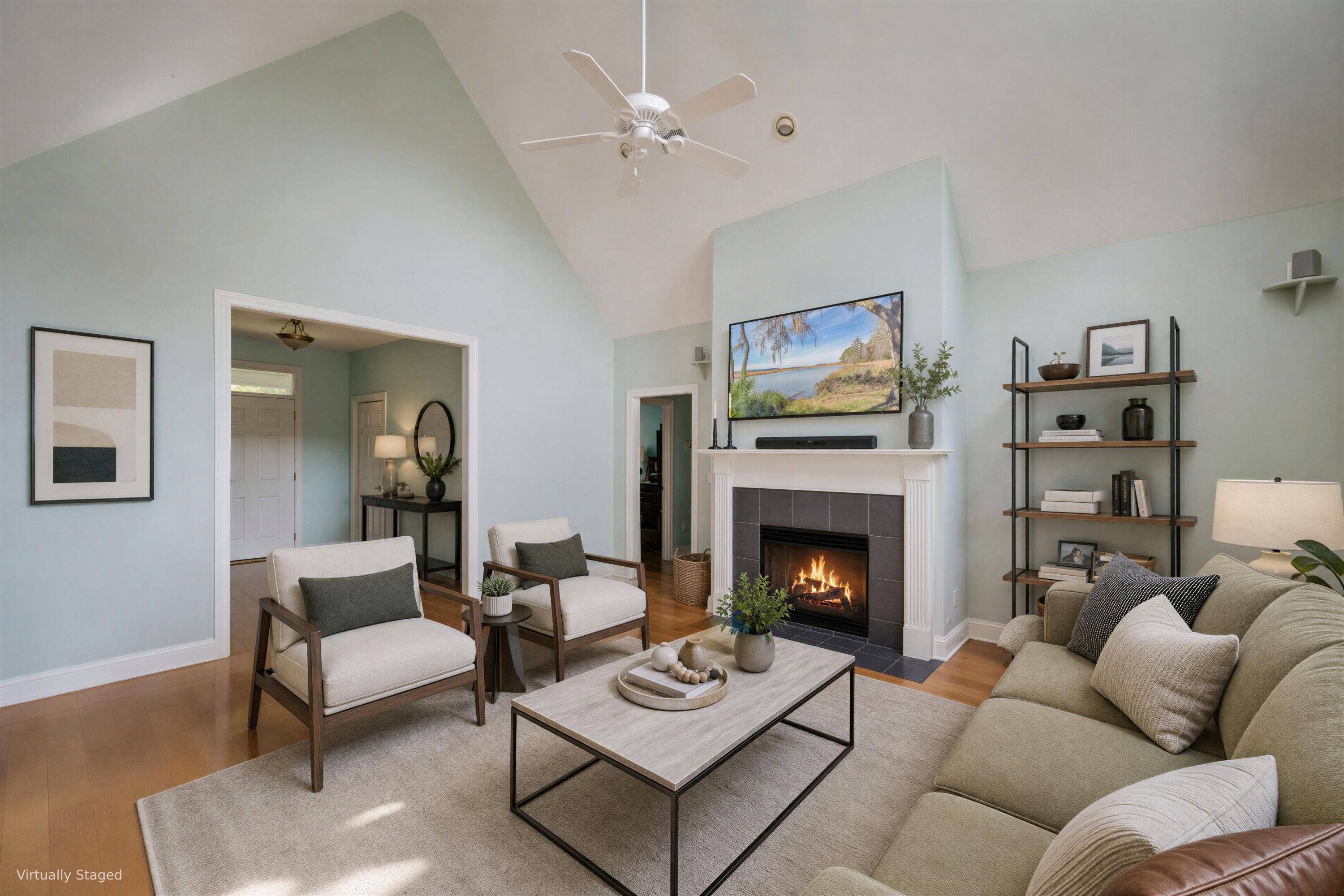 Living room with a vaulted ceiling, lit fireplace, and staged seating area.