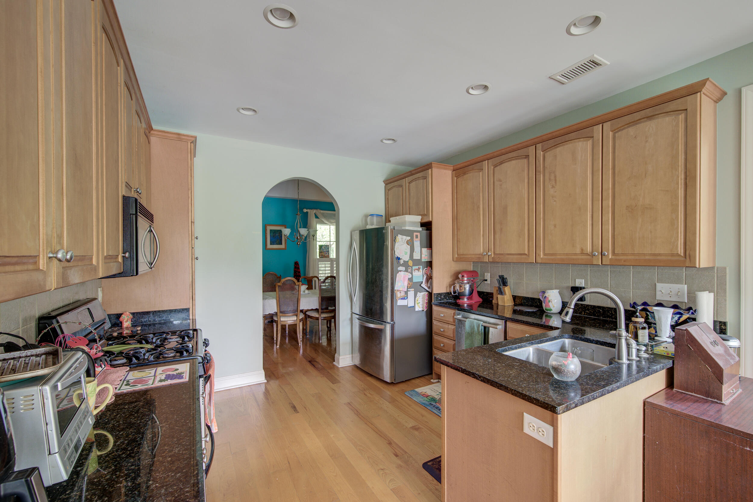 Kitchen with light wood cabinets, granite counters, an island sink, and stainless steel appliances.