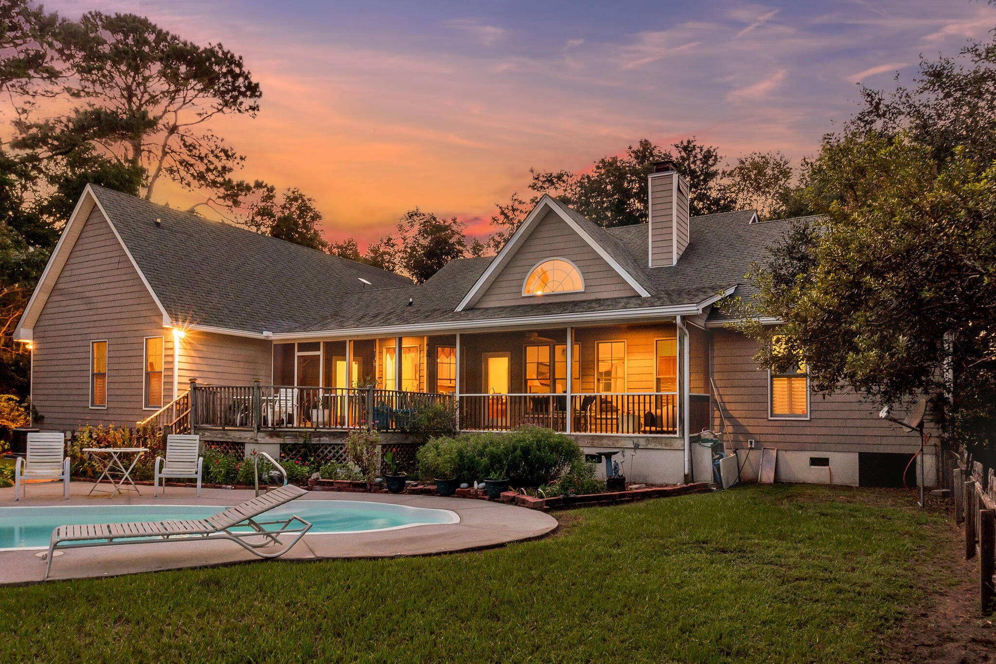 Home’s rear porch and swimming pool glow in the evening light.