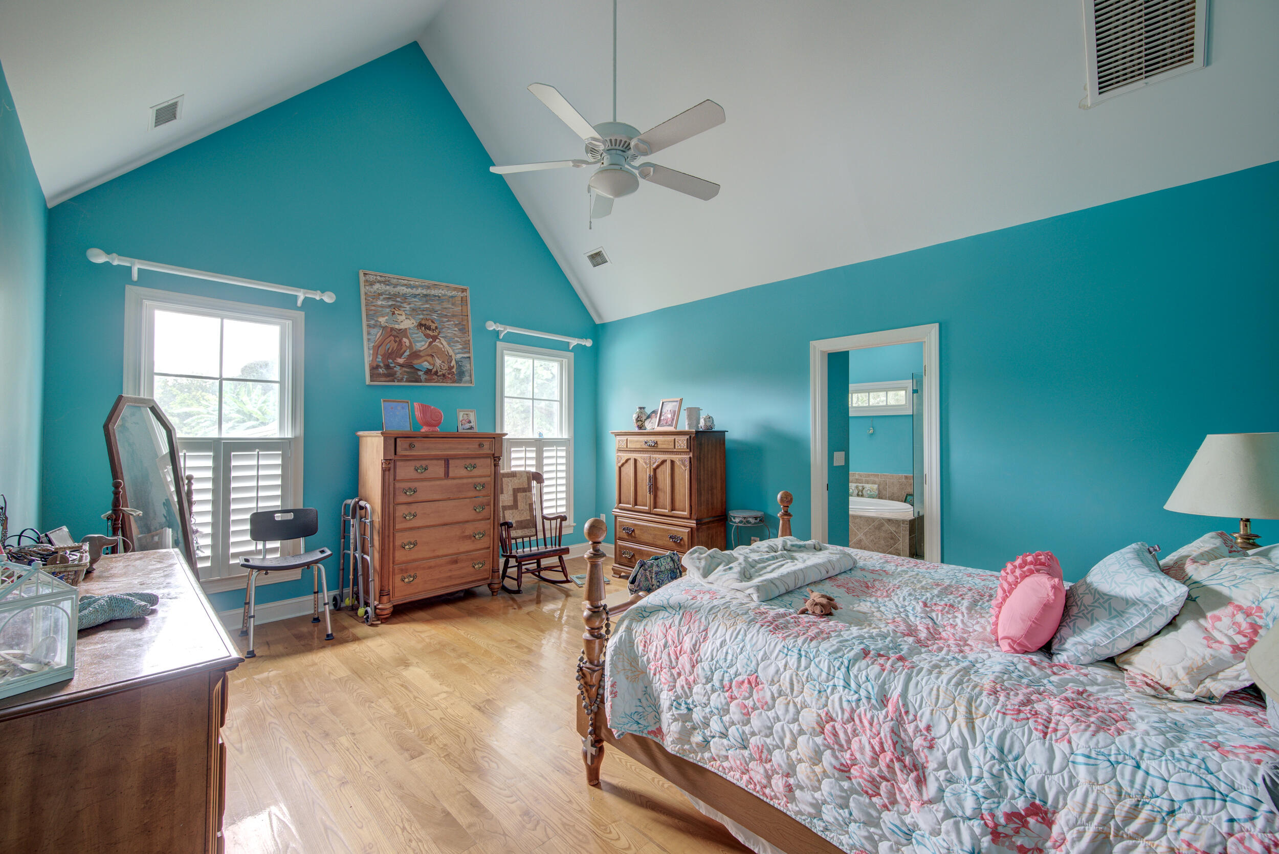 Bedroom with teal walls, a vaulted ceiling, and a wooden four-poster bed with floral bedding.