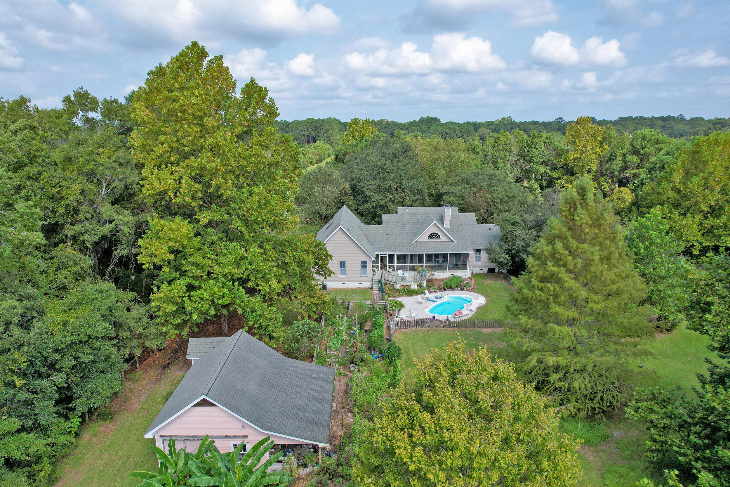 Aerial view of a wooded home with a backyard swimming pool and detached outbuilding.