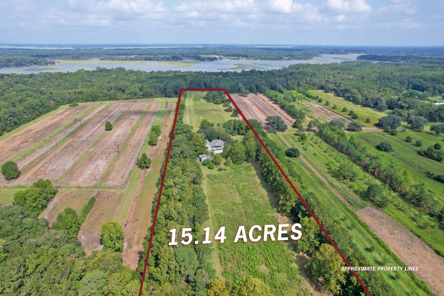 Aerial view of a 15.14-acre property outlined in red, with a house, pool, fields, and distant marshland.