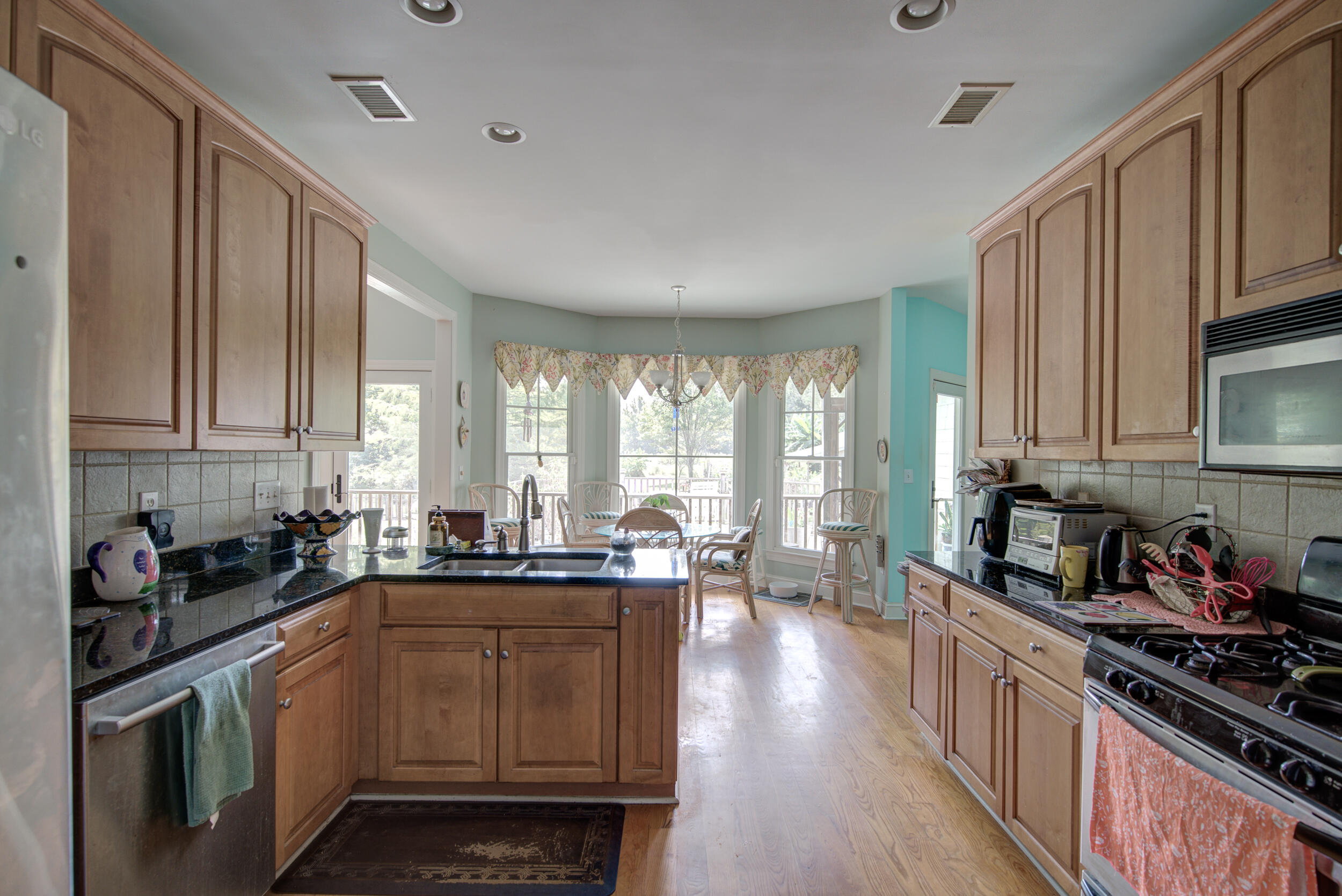 Kitchen with wood cabinetry, a central sink island, and a window-side dining nook.