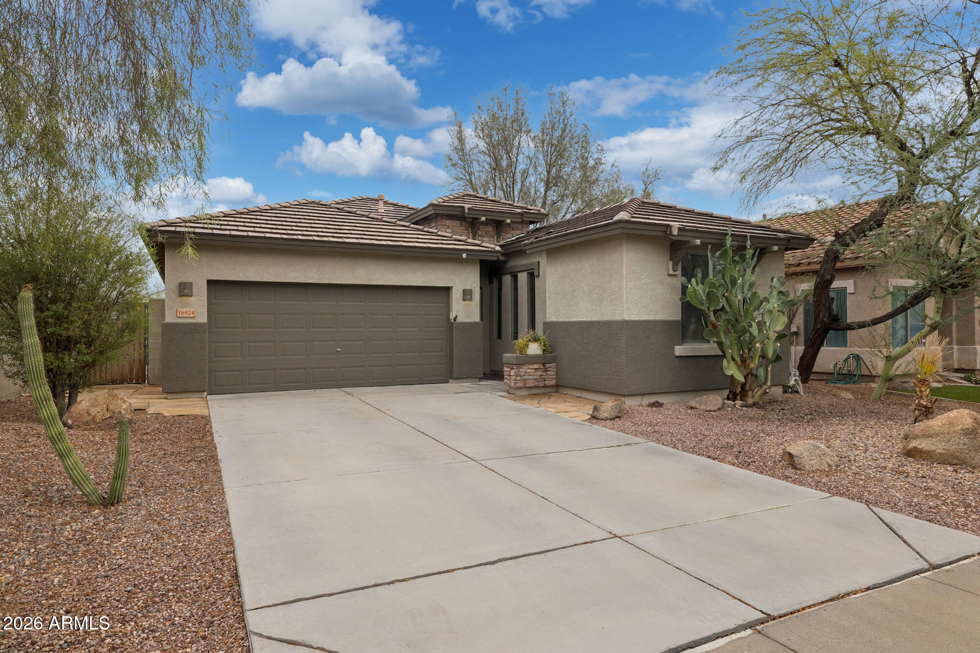 Single-story stucco home with a tile roof, two-car garage, and desert landscaping.