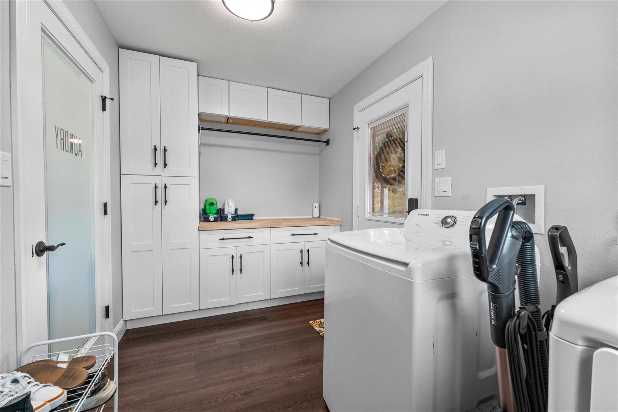 Laundry room with white built-in cabinetry, wood folding counter, and washer and dryer.