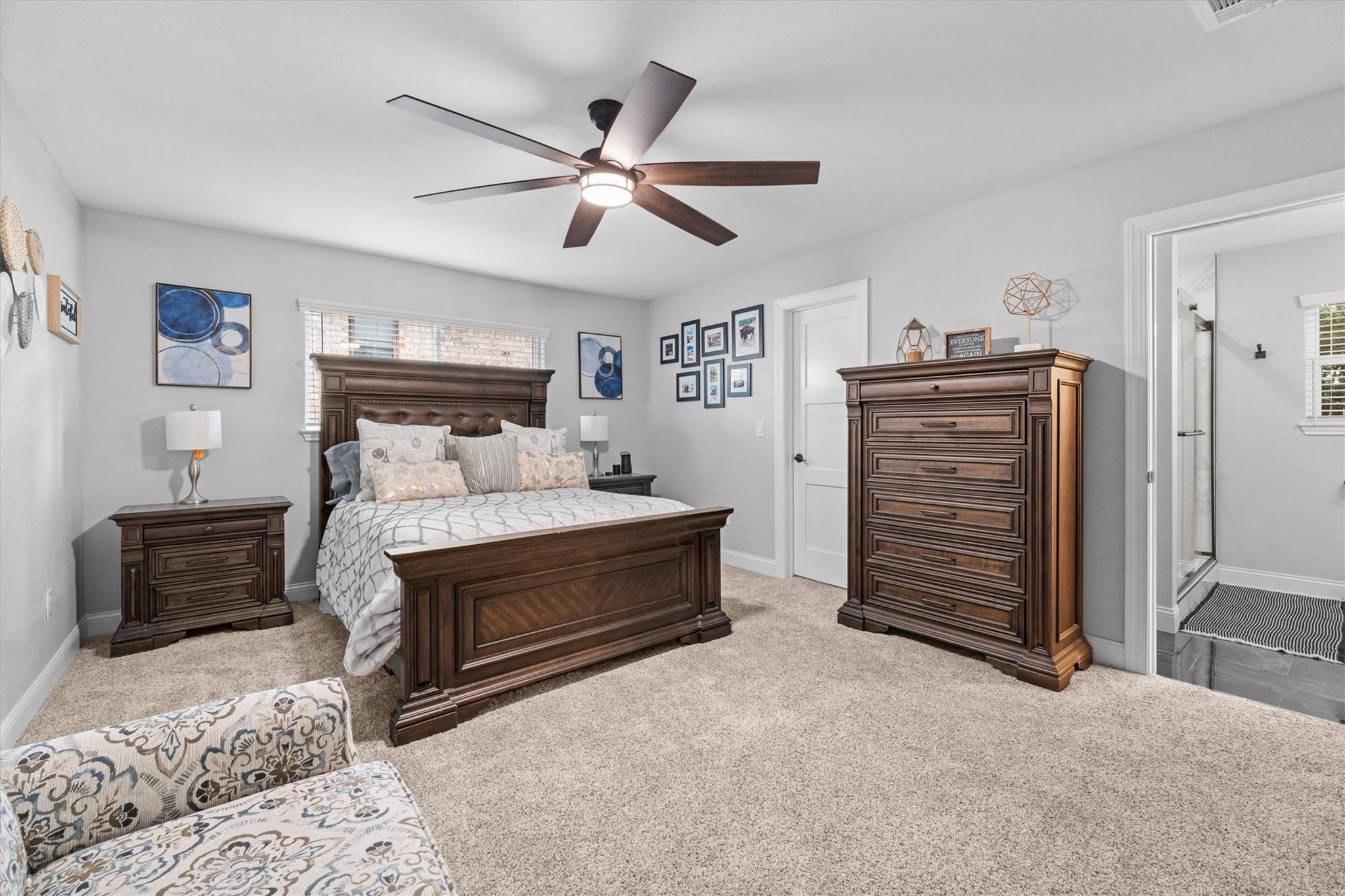 Furnished bedroom with a dark wood bed and matching dresser, neutral carpet, and an adjoining bathroom.