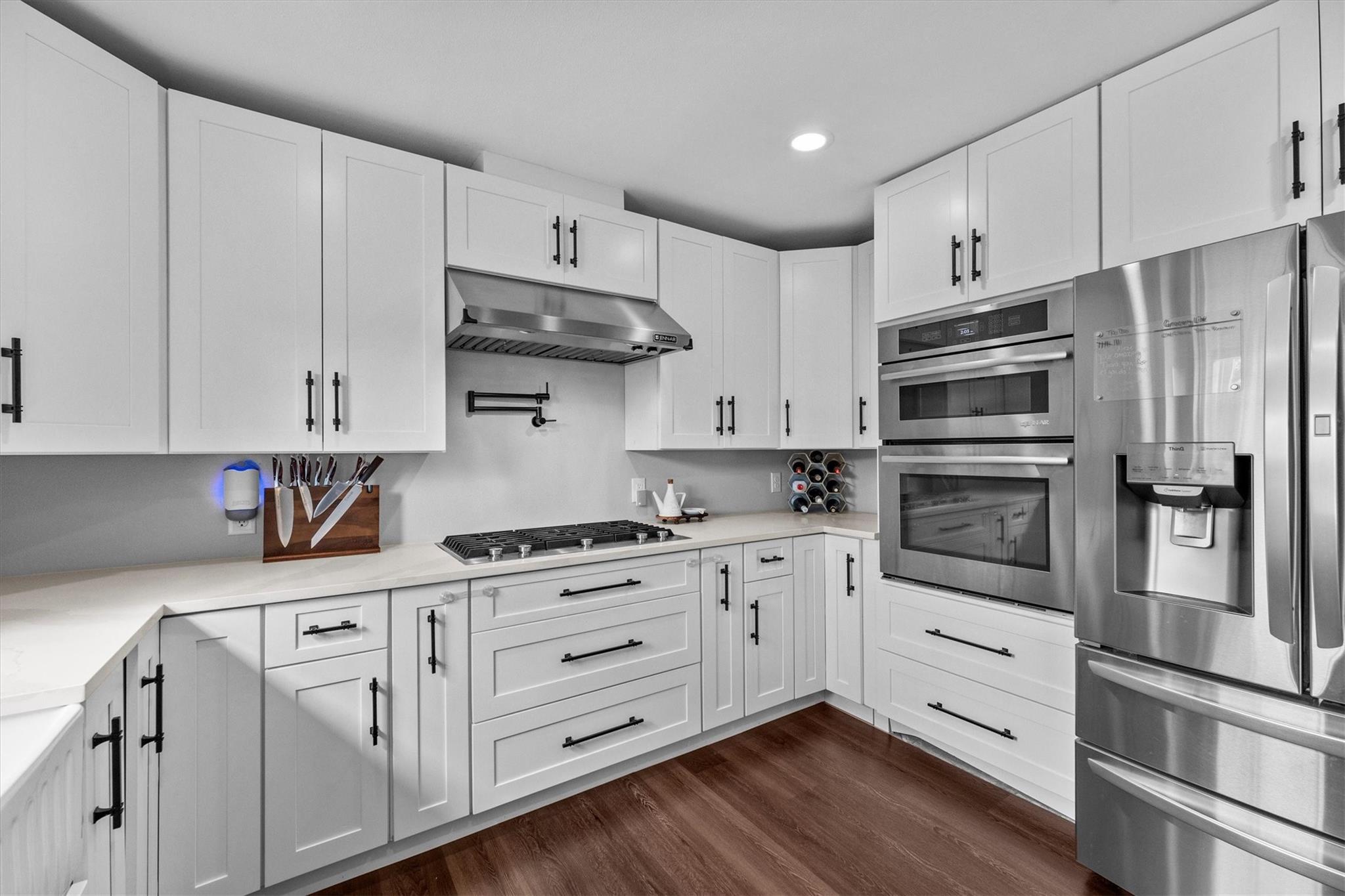 Modern kitchen with white Shaker cabinets, a gas cooktop, built-in ovens, and a stainless steel refrigerator.