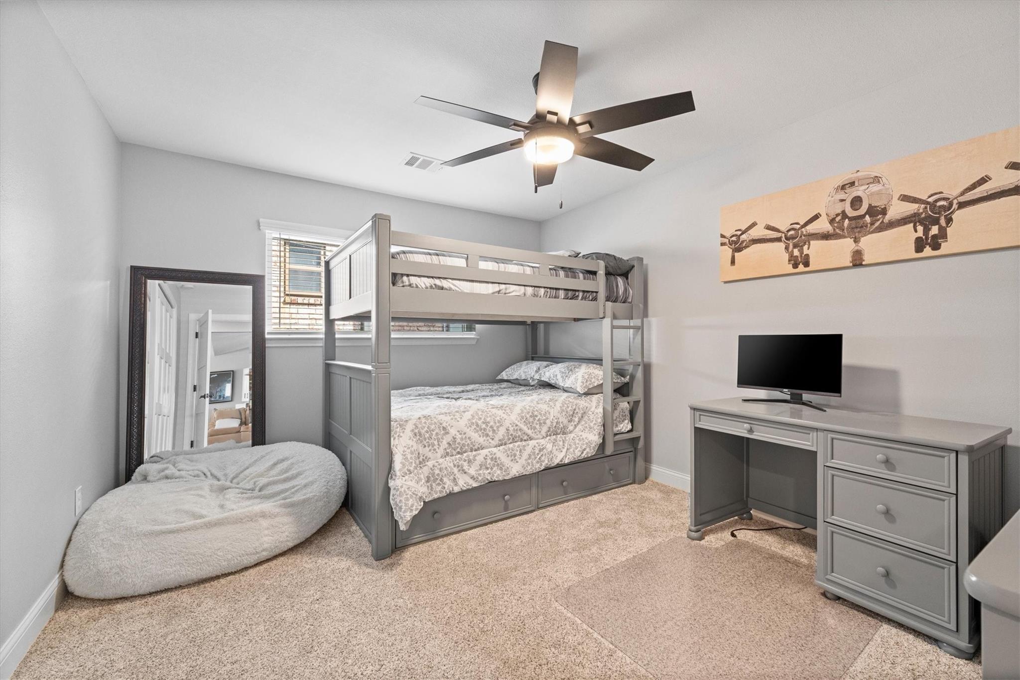 Bedroom with a gray bunk bed, desk and television, and airplane artwork on the wall.
