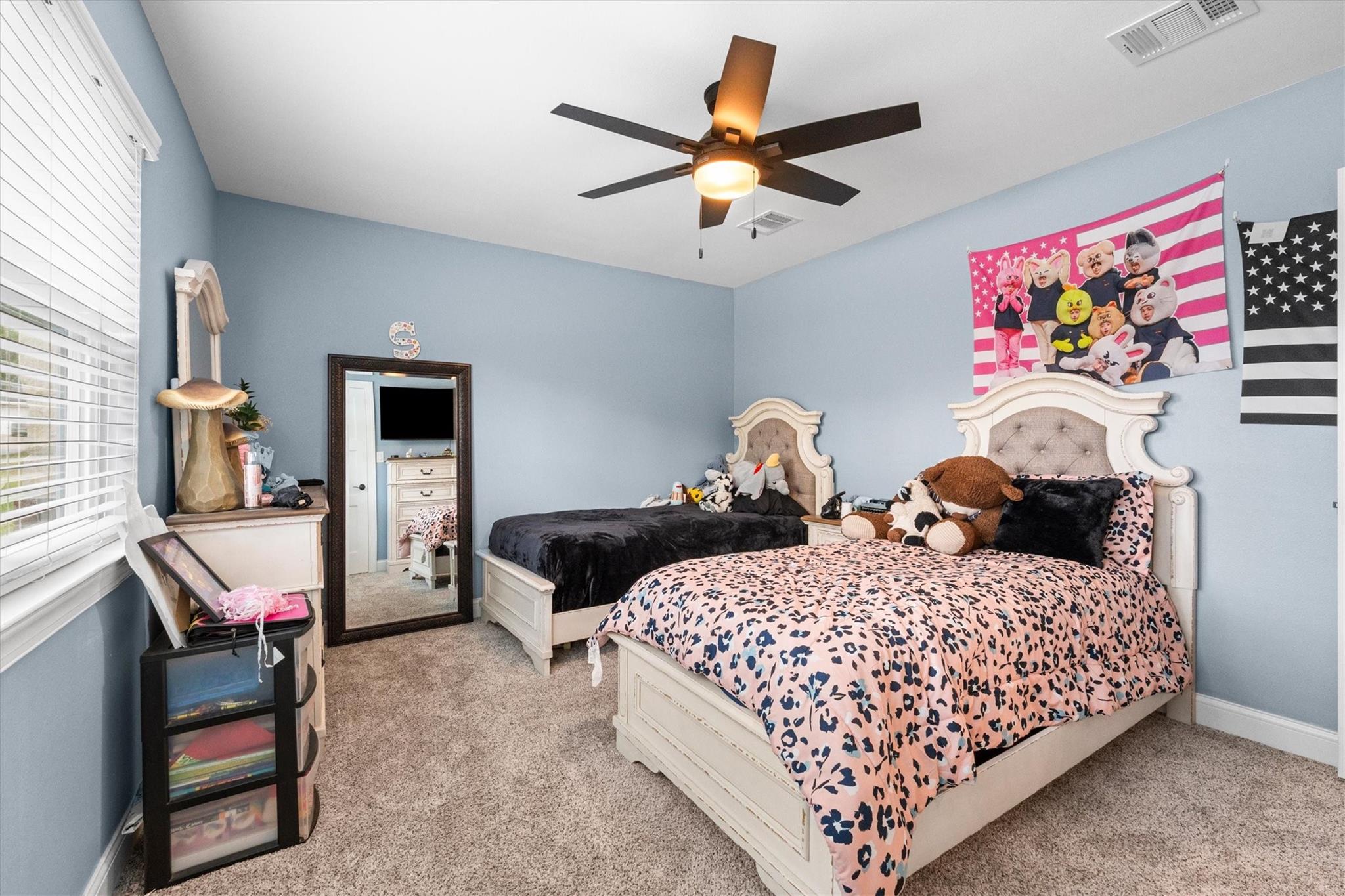 Bedroom with two white beds, blue walls, and a ceiling fan.