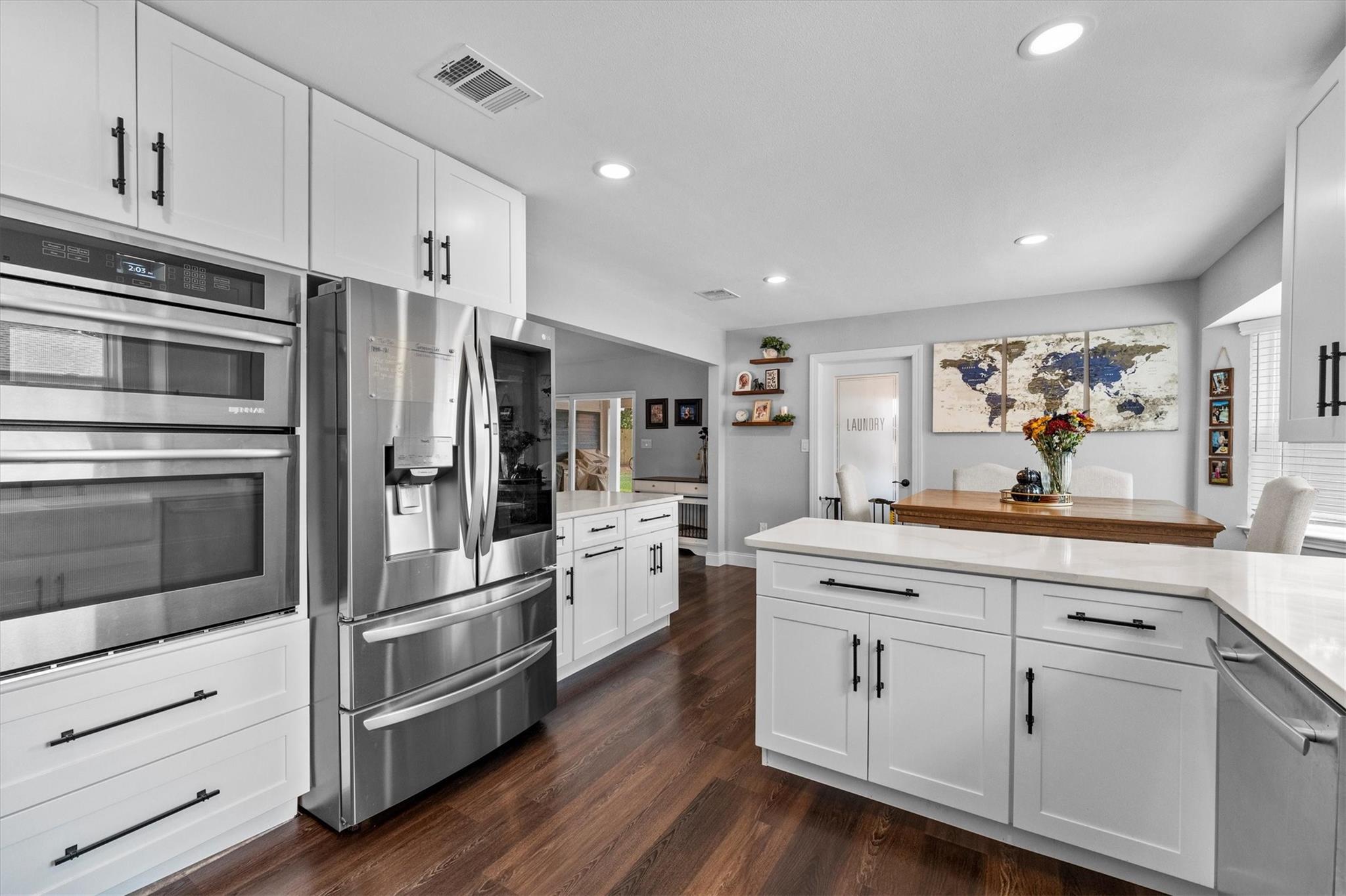 Renovated kitchen with white cabinetry, a large island, stainless steel appliances, and an adjoining dining area.