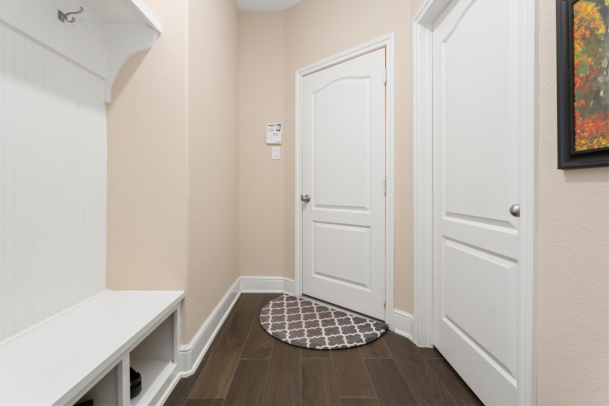 Entryway with a white built-in bench, paneled doors, dark tile flooring, and a patterned rug.