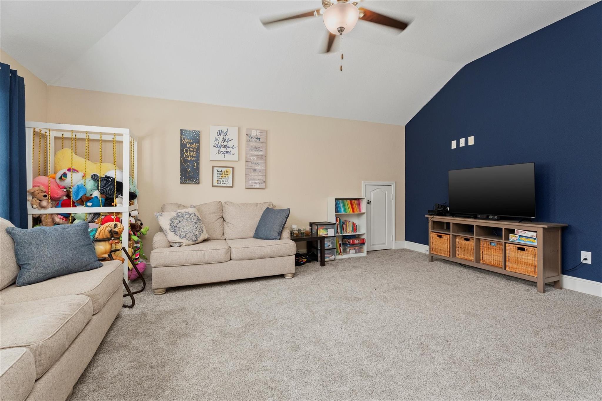 Family room with beige sofas, a toy-filled bunk bed, and a TV against a navy accent wall.
