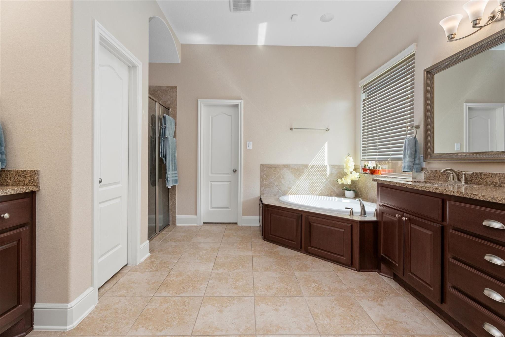 Primary bathroom with a soaking tub, glass shower, and dark wood vanity cabinets.