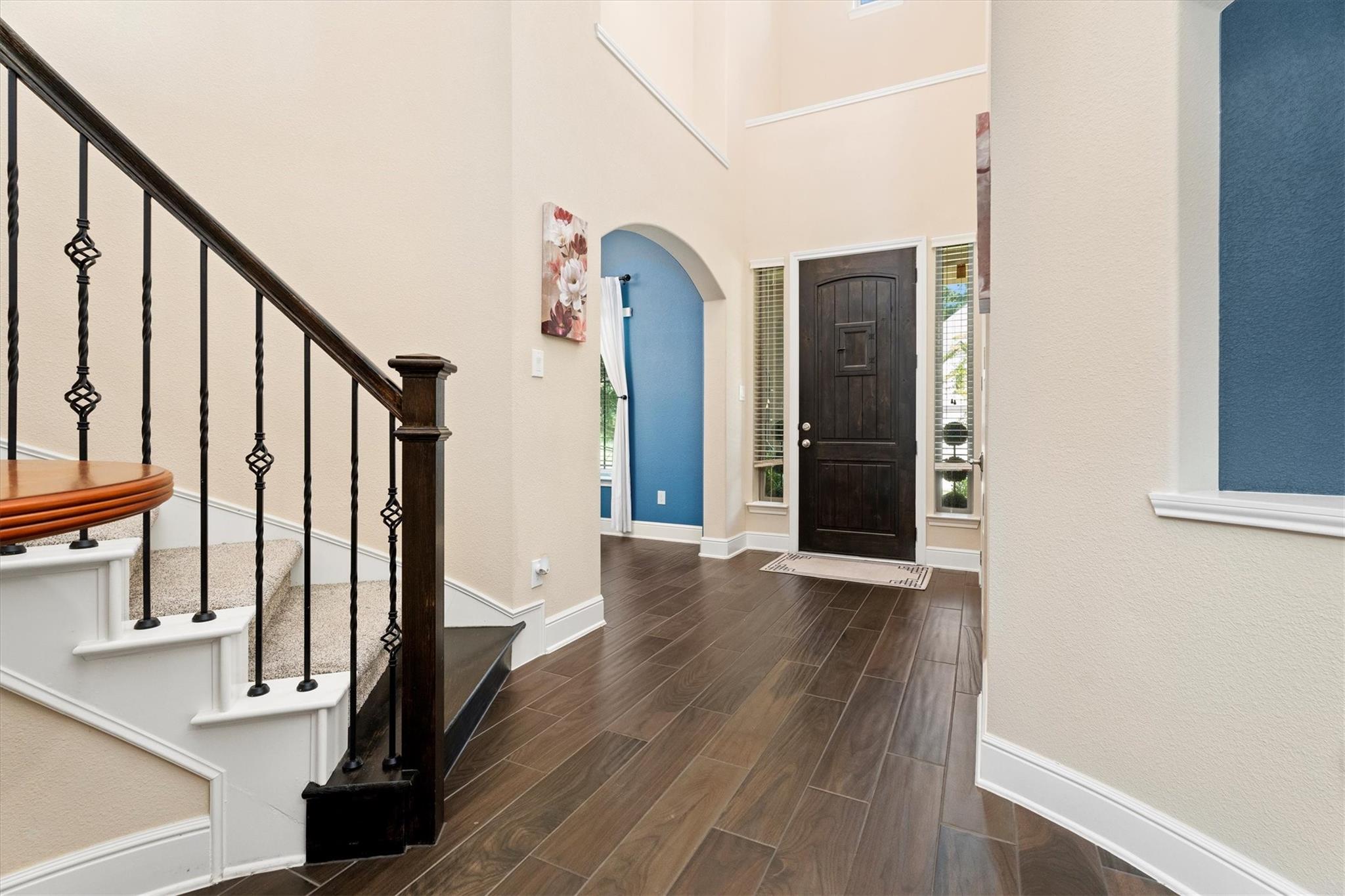 Entry foyer with a carpeted staircase, dark front door, and blue arched alcove.