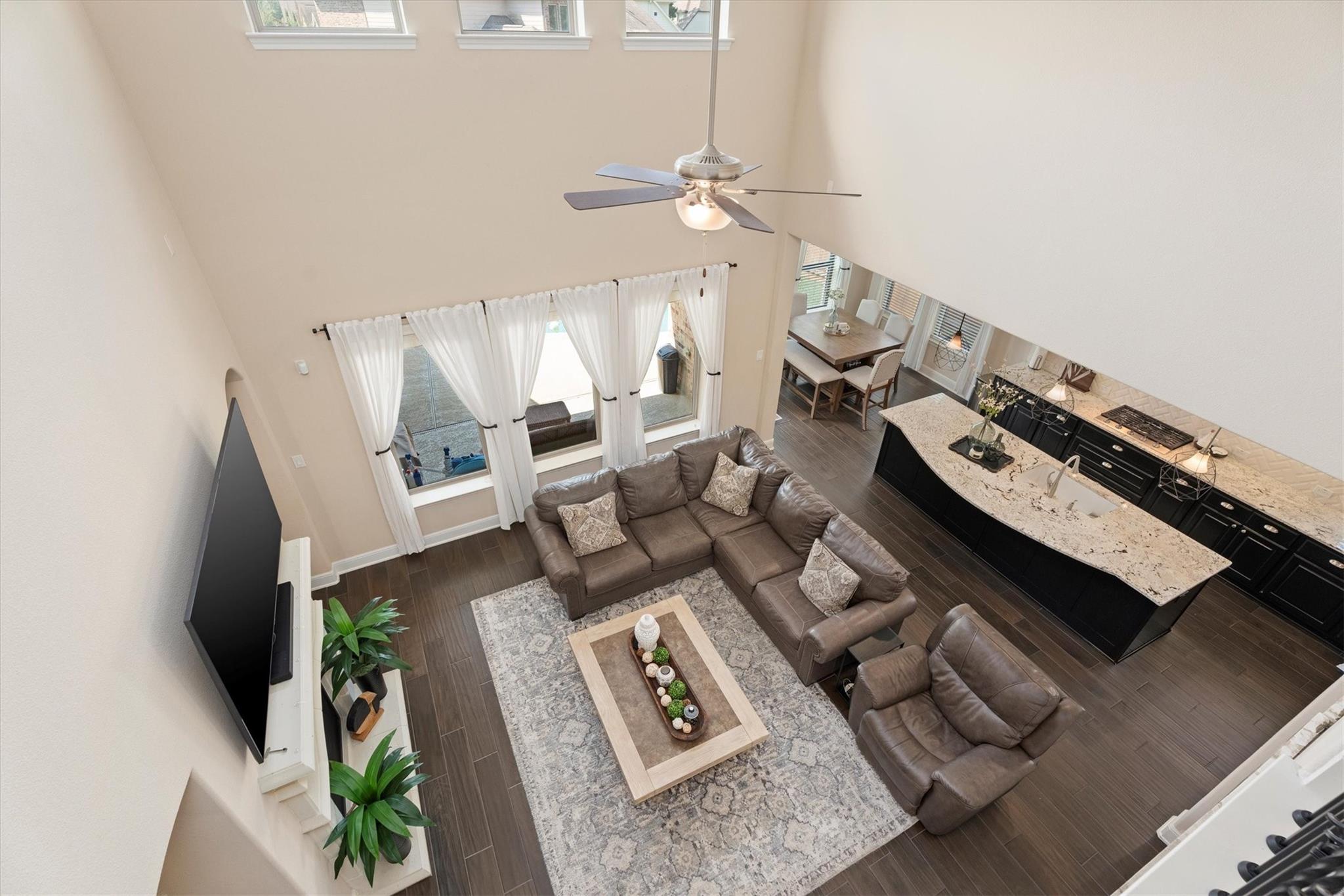 Open-plan living room with double-height ceiling, leather seating, and a kitchen island.