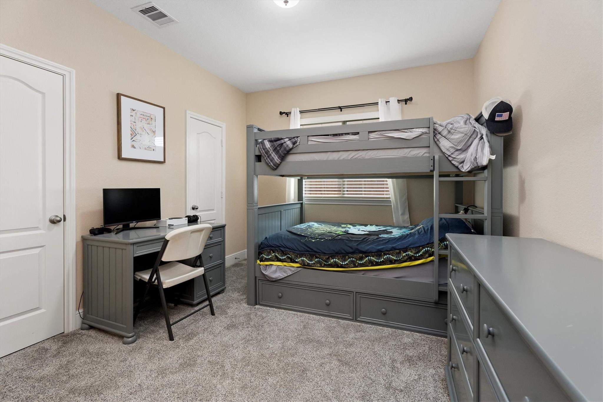 Bedroom with a gray bunk bed, trundle, desk, and matching dressers.
