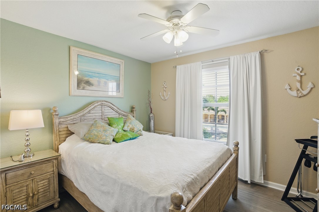 Bedroom with a weathered wood bed, coastal artwork, anchor decorations, and a curtained window.