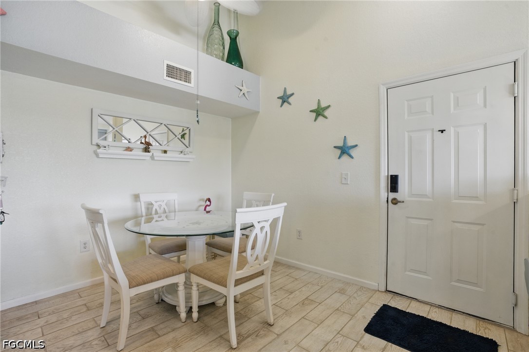 Dining nook with a round glass table, white chairs, tiled floor, and entry door.
