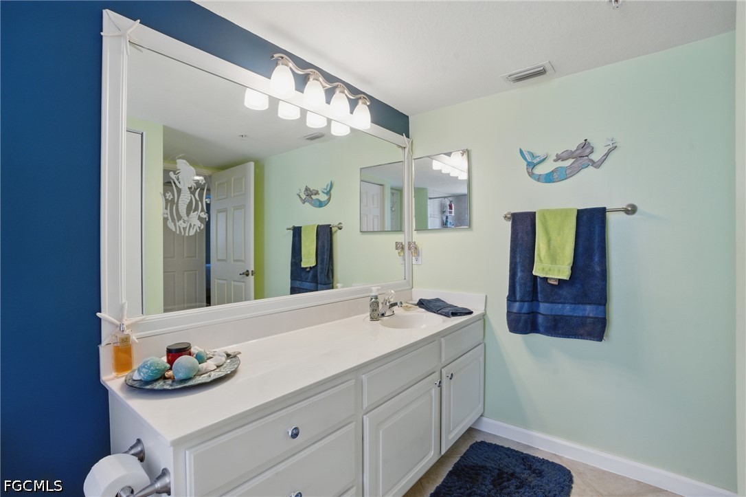 Bathroom with a long white vanity, large mirror, and mermaid decorations on pale green walls.