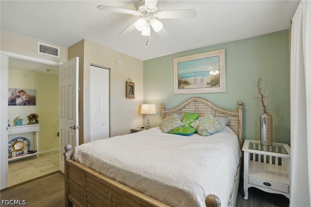 Bedroom with a large bed, sage-green accent wall, and framed beach artwork.