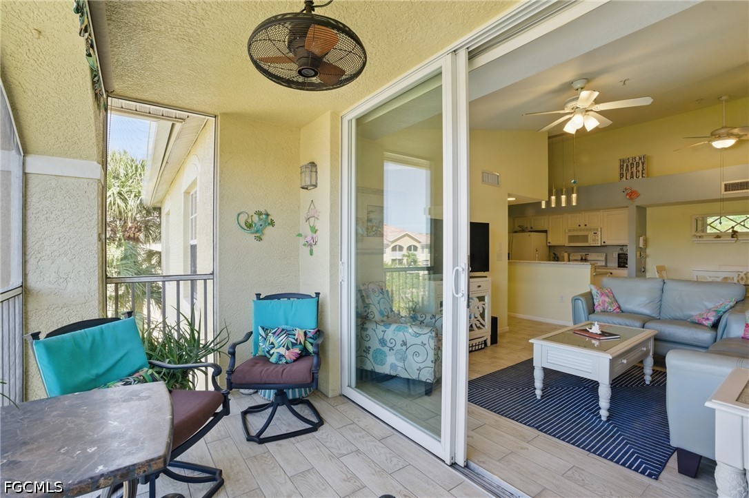 Screened lanai with turquoise seating and ceiling fan opening onto a furnished living room.