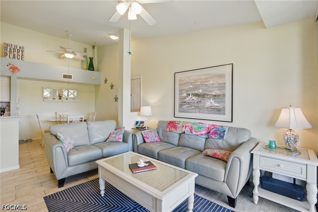 Furnished living room with gray sofas, colorful cushions, and an open dining area.