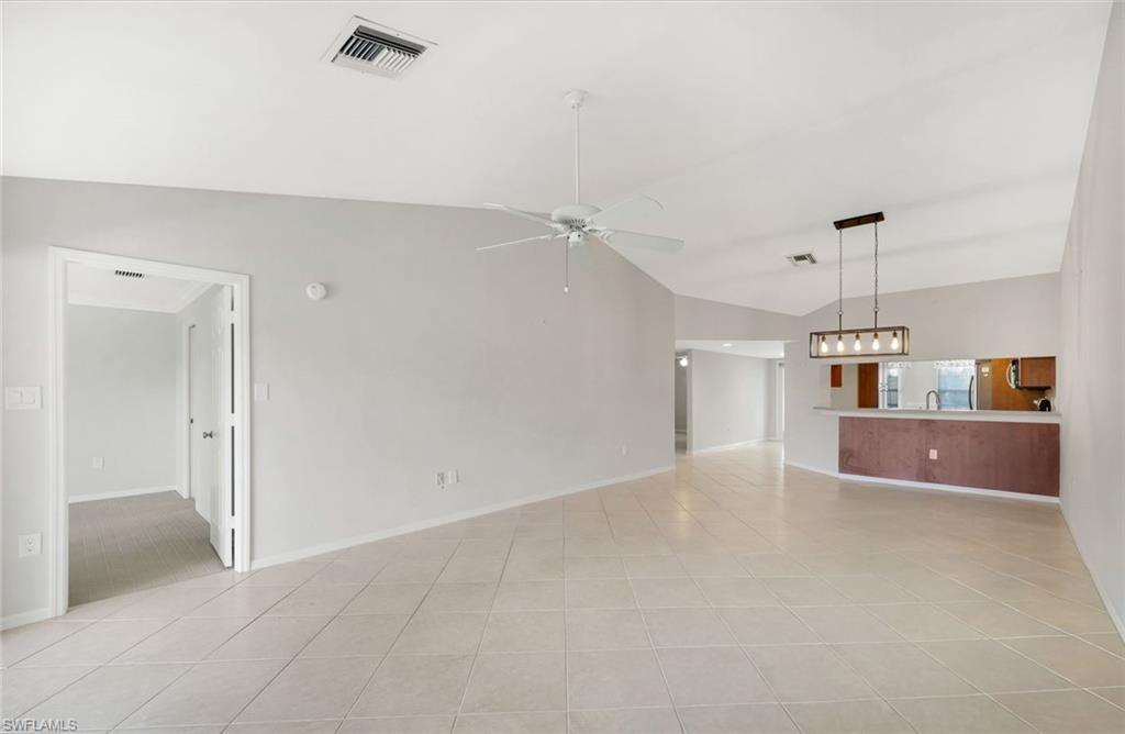 Open-plan living area with vaulted ceiling, tiled floors, and a kitchen pass-through.