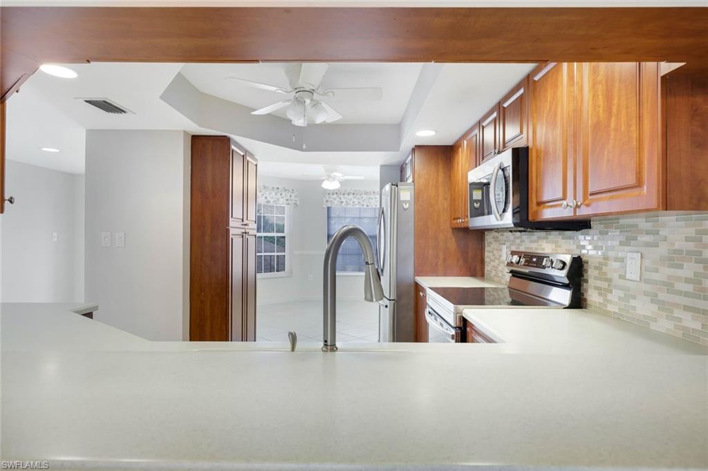 Kitchen with warm wood cabinets, stainless steel appliances, and a broad white peninsula.
