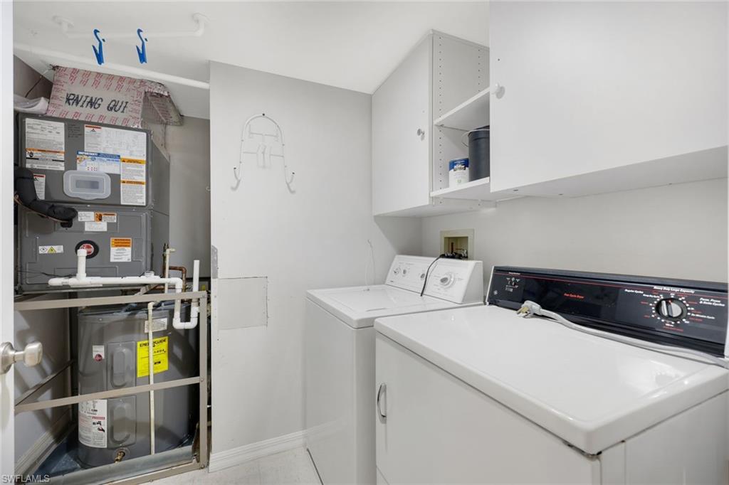 Laundry room with washer, dryer, overhead cabinets, and a utility unit behind a safety rail.