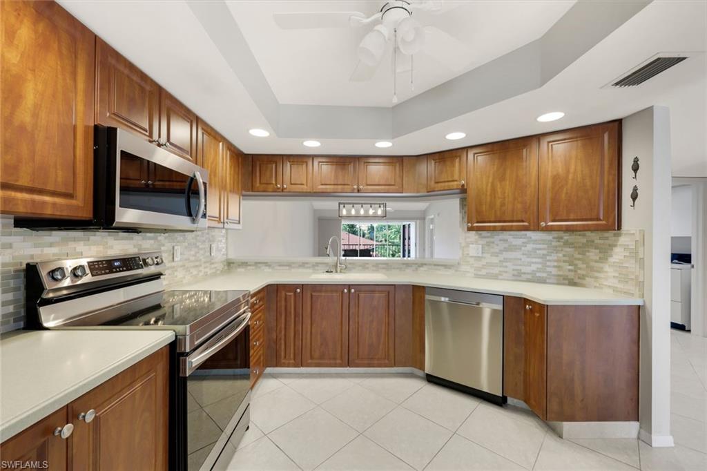 Kitchen with warm wood cabinets, stainless steel appliances, and a window above the sink.