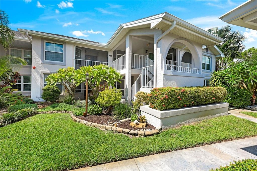 Two-story condominium exterior with arched balconies, white railings, and landscaped gardens.