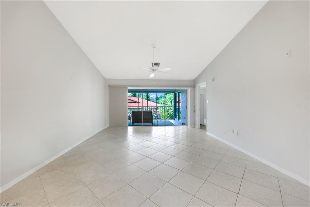 Empty living room with tiled floors and sliding glass doors opening to a balcony.
