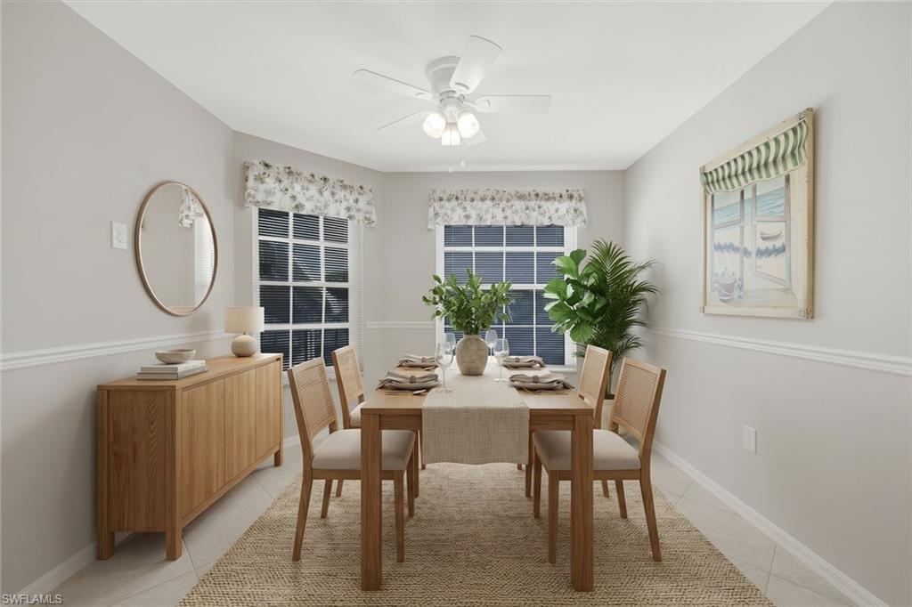 Staged dining room with a wooden table, woven rug, and leafy plants beside two windows.