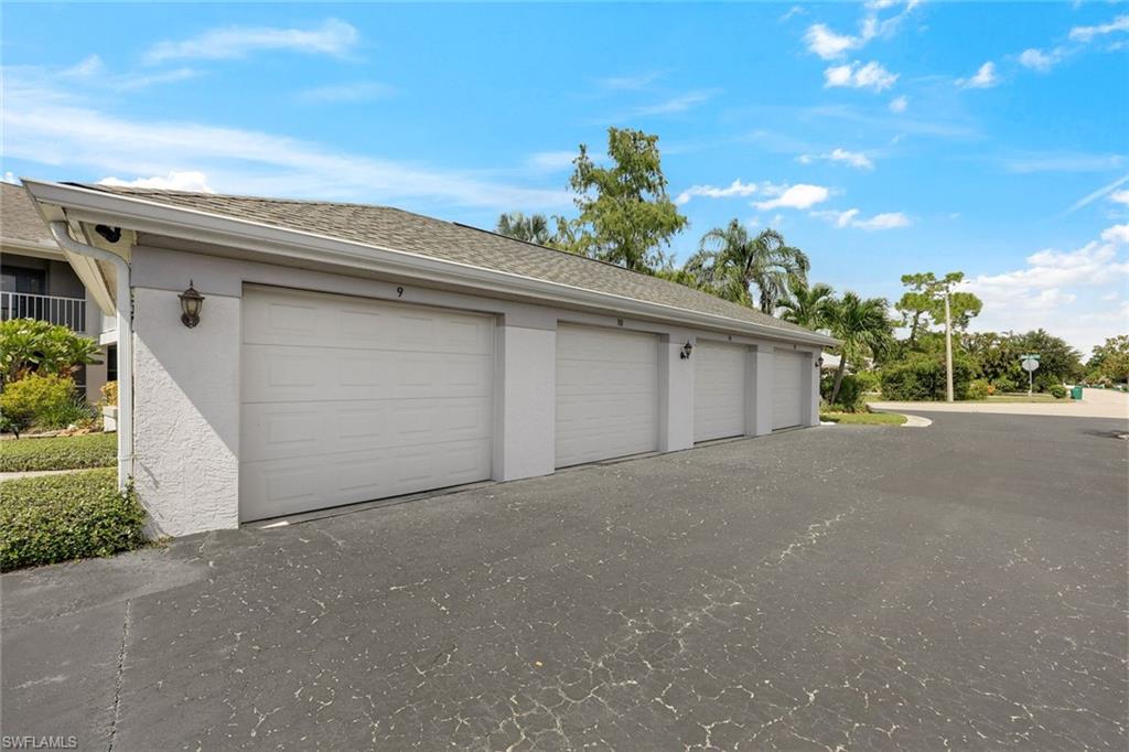 White garage units with closed doors beside a paved parking area.