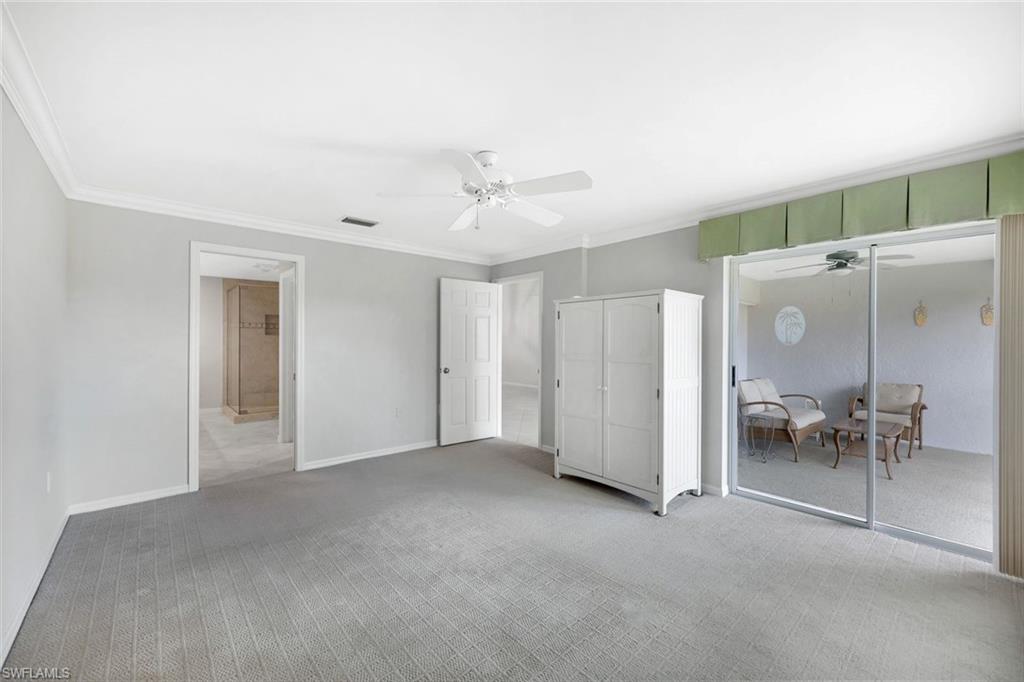 Mostly empty bedroom with gray carpet, a white wardrobe, and sliding doors to a lanai.