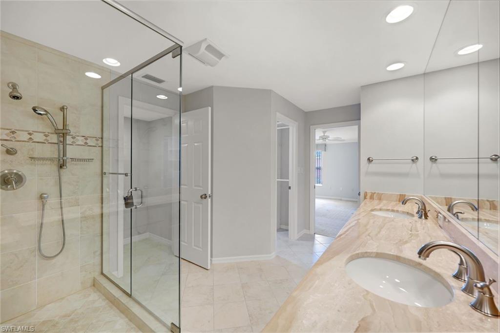 Bathroom with a glass-enclosed shower and double-sink marble vanity.